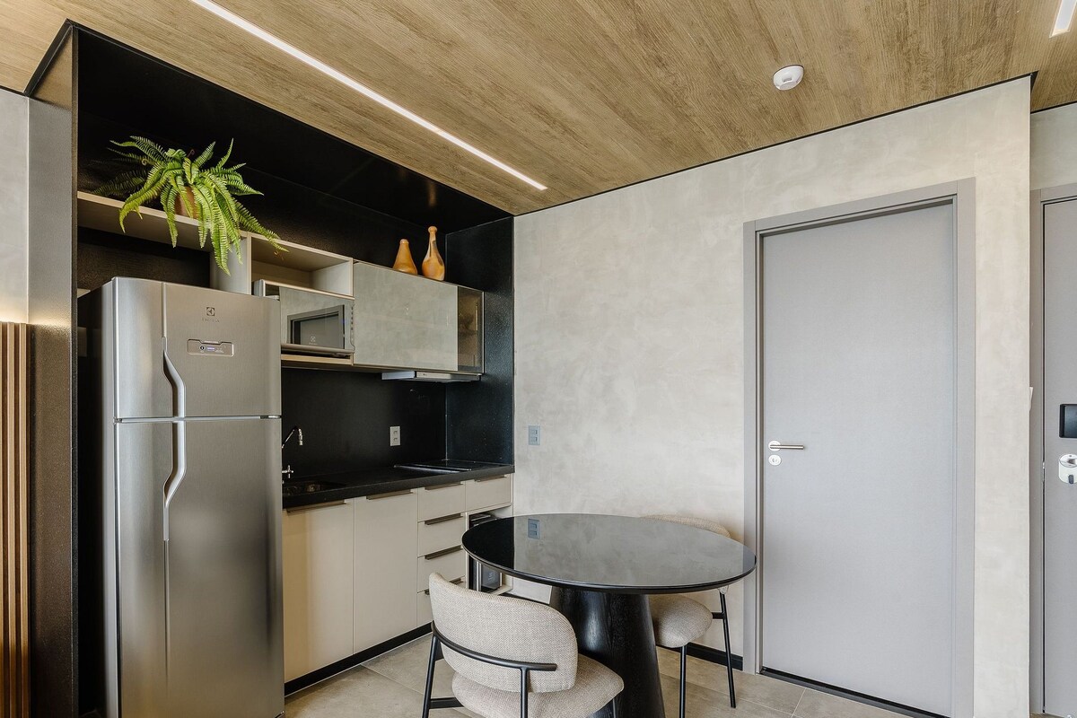 Une cuisine compacte équipée d’un réfrigérateur, d’un four à micro-ondes et d’une petite table à manger avec des chaises.