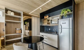 A modern kitchen with a black countertop, stainless steel appliances, and wooden shelving.