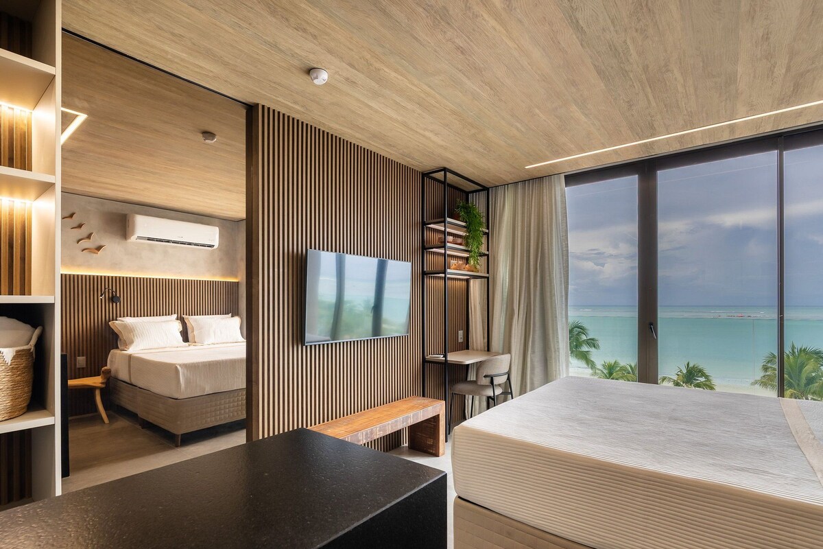 Une chambre d’hôtel moderne dotée d’un grand lit, d’une télévision, d’un bureau et d’un balcon avec vue sur la mer.