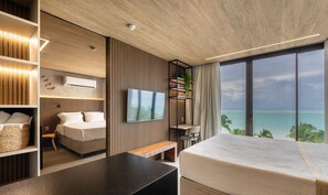Une chambre d’hôtel moderne dotée d’un grand lit, d’une télévision, d’un bureau et d’un balcon avec vue sur la mer.