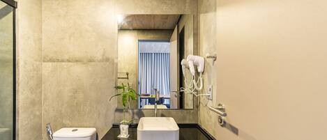 A modern bathroom with a large mirror, a sink, a toilet, and a hairdryer on the wall.
