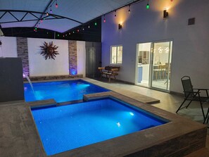 Una piscina interna con bordi in pietra, una decorazione a forma di sole e una panca.