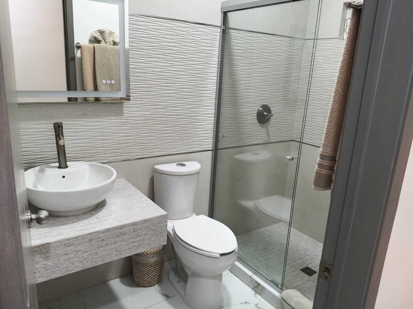 Et badeværelse med vask, toilet og brusekabine.
