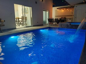 An indoor swimming pool with a clear view of the surrounding area, including a dining area with tables and chairs, and a kitchen with a barbecue grill. - Beautiful house with private pool, only 5 minutes from the sea, comfortable and safe. (Puerto Peñasco)