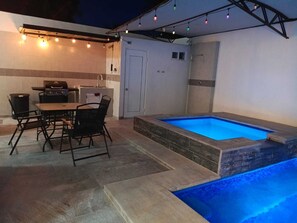 An outdoor patio with a dining table and chairs, a barbecue grill, a hot tub, and string lights. - Beautiful house with private pool, only 5 minutes from the sea, comfortable and safe. (Puerto Peñasco)