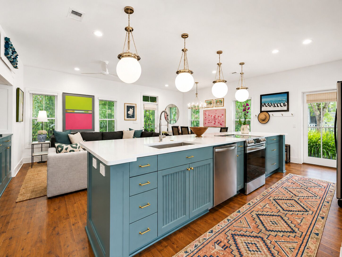 A modern kitchen with a large island, pendant lighting, and a view of the outdoors.