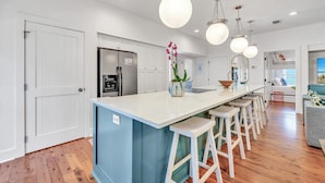 Una cocina moderna con una isla central, taburetes de bar e iluminación colgante.