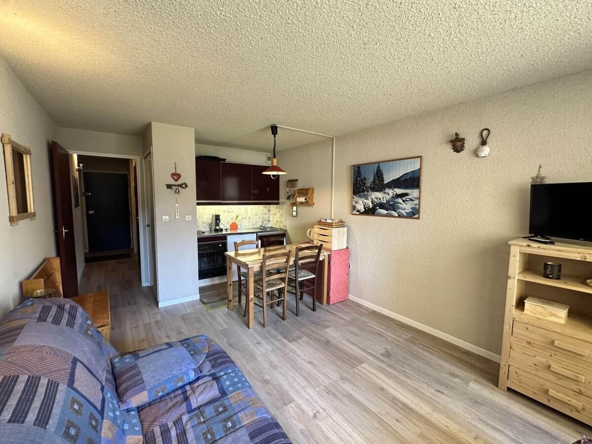 A compact living space with a kitchenette, a dining area, and a TV stand.