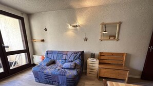 A cozy room with a large sofa, a wooden bench, a small table, and a dresser. - 1st floor, balcony, tv, 32m², Villard de Lans (Corrençon-en-Vercors)