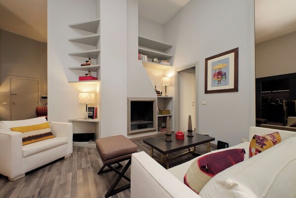 Una sala de estar moderna con un sofá blanco, una mesa de centro y una escalera con estantes.