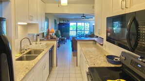A kitchen with white cabinets, a microwave, a stove, and a ceiling fan. - Lovely Gentle Winds 2-bedroom condo! (St. Croix)
