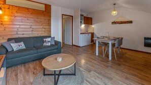 A modern living room with a sofa, a coffee table, and a dining area with a table and chairs.
