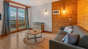 A cozy living room with a wooden wall, a sofa, a small table, and a view of a balcony.
