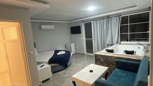Un salon moderne avec un canapé, une table basse, un téléviseur et une salle de bain dotée d’une baignoire.