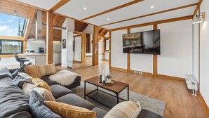 Un salon moderne avec un grand canapé, une table basse et un téléviseur à écran plat fixé au mur.