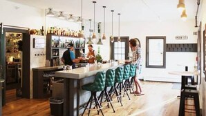 A bar area with a counter, stools, and hanging lights.
