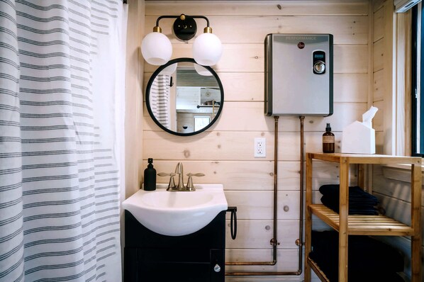 A wooden-paneled bathroom with a white sink, a round mirror, and a towel rack.
