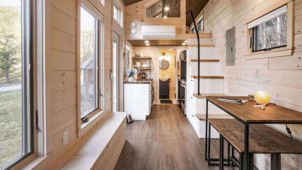 A compact kitchen with wooden walls, a central island, and a dining area with benches.