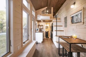 A compact kitchen with wooden walls, a central island, and a dining area with benches.