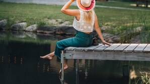 A person sitting on a wooden dock by a calm body of water, with a house and trees in the background. - Sage House Glamping Retreat with Hot Tub + Sauna (Chester)