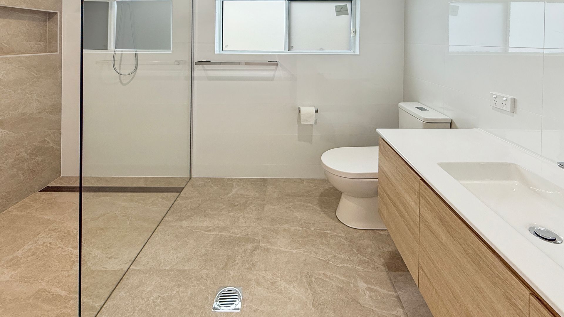 Une salle de bain moderne avec une douche à parois de verre, des toilettes et un lavabo avec un meuble-vasque en bois.