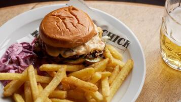 Un plato con una hamburguesa, papas fritas y ensalada de col sobre una mesa de madera.