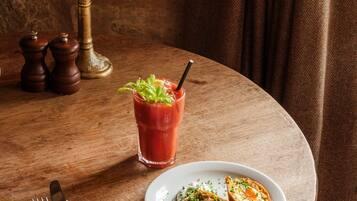 Un tavolo con una candela, un cocktail Bloody Mary e un piatto di cibo.