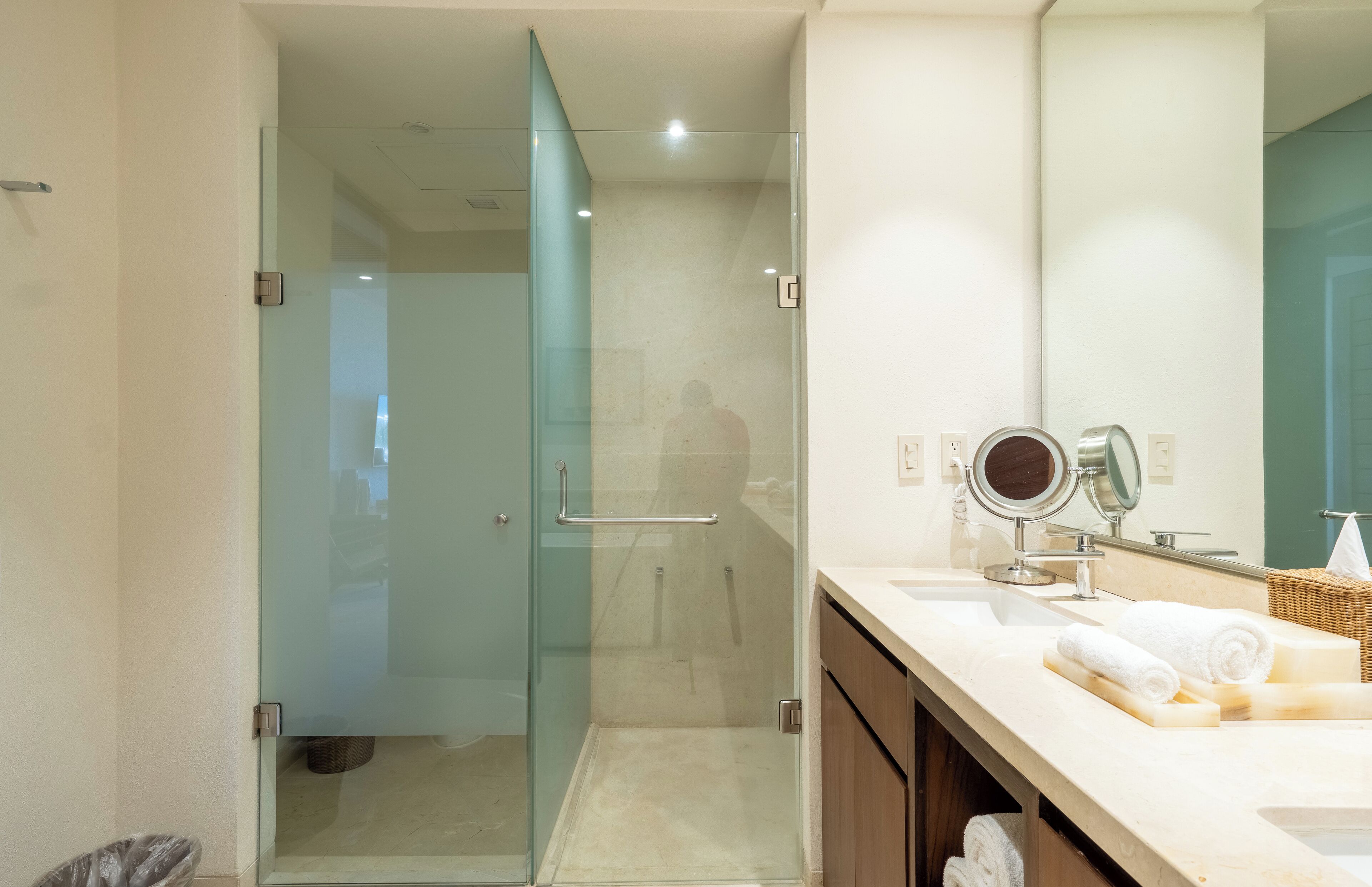 Une salle de bain moderne avec une douche à parois de verre, un meuble-lavabo avec un miroir et des serviettes soigneusement rangées.
