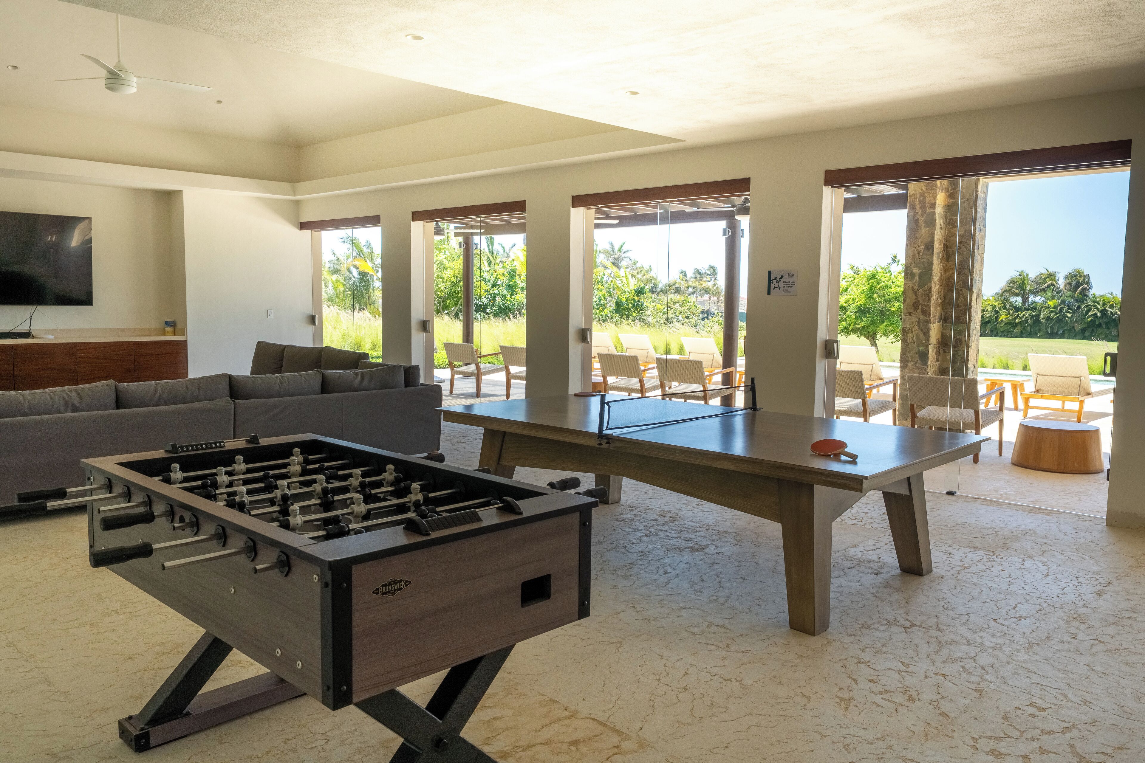 A spacious living area with a foosball table, a sofa, and a dining table with chairs.