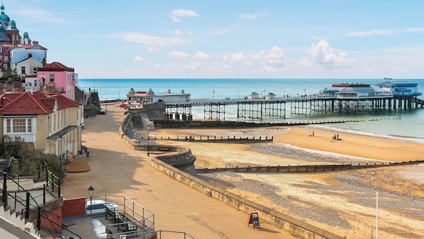 A coastal town with a pier extending into the sea, a sandy beach, and buildings with domed roofs. - A superb holiday choice. (Rackheath, near Wroxham)