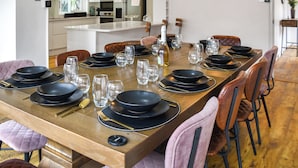 A dining area with a long wooden table set for a meal, surrounded by chairs with cushioned seats. - A superb holiday choice. (Rackheath, near Wroxham)