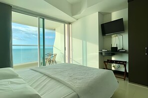 A hotel room with a bed, a TV, a desk with a chair, and a balcony with a view of the sea. - Palmetto Eliptic  (Cartagena)