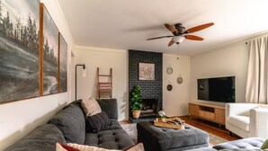 A living room with a sectional sofa, a fireplace, a ceiling fan, and a television. - Charming 3-bedroom house, convenient location Overland Park (Overland Park)
