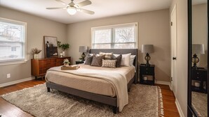 A bedroom with a bed, a ceiling fan, two bedside tables with lamps, a dresser, and a window with blinds. - Charming 3-bedroom house, convenient location Overland Park (Overland Park)