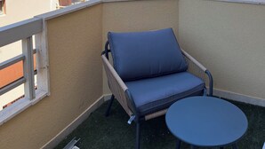 A balcony with a blue cushioned chair and a small table, overlooking a marina with boats and palm trees. - Magnificent renovated air-conditioned rooftop terrace/50m from the sea. (CAVALAIRE SUR MER)