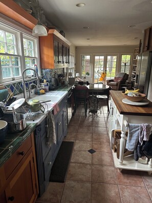 Una cocina con una isla grande, armarios de madera y un comedor con una silla y una mesa.