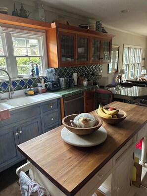 A kitchen with wooden cabinets, a tiled backsplash, and a window overlooking greenery.