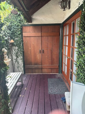 A wooden door with a green frame, a bench, and a small table with a mat in front.