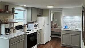 Una cocina compacta equipada con estufa, microondas, refrigerador y pileta.