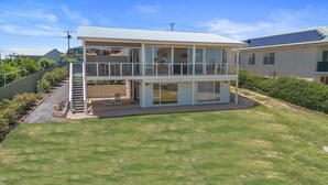 A two-story house with a balcony, a covered patio, and a solar panel on the roof. - Norman Views - 20 Panorama Crescent (Normanville)