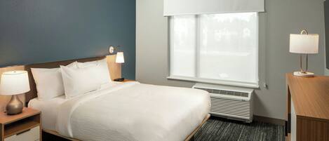 Hotelkamer met een bed, twee bedlampen, een raam met zonwering, een verwarming en een nachtkastje van hout.