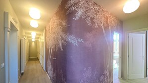 Un pasillo con un gran mural en la pared, suelo de madera y una puerta al final.