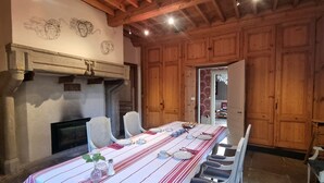 Un comedor con una mesa larga dispuesta para una comida, paneles de madera en las paredes y una chimenea.