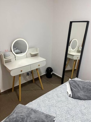 A bedroom with a white vanity, a round mirror, and a large mirror. - Acogedor Apartamento en el Corazón de la CDMX – SúperAnfitrión Coyoacán (Ciudad de México)