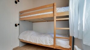 Una cama litera con dos niveles, un colchón blanco en la cama inferior y estructura de madera.