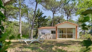 Una casa pequeña y moderna con puerta y ventanas de vidrio, rodeada de árboles.