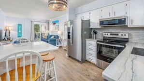 A modern kitchen with white cabinetry, stainless steel appliances, and a marble countertop.