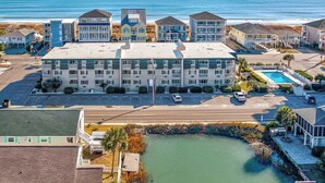 A beachfront hotel with multiple buildings, a swimming pool, and a parking lot.