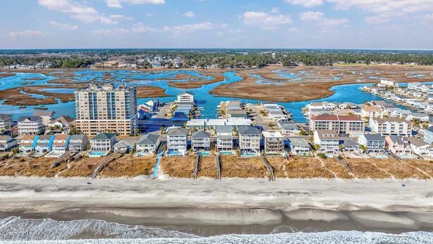 An aerial view of a coastal resort with beachfront properties, a marina, and a marshy area.