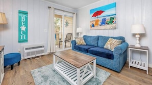 A living room with a blue sofa, a wooden coffee table, and a painting of a beach scene.